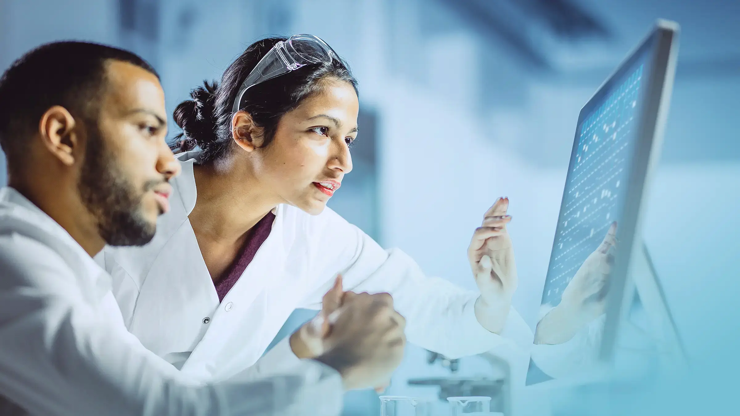 Male and female medical device designers looking at a project on a computer monitor.